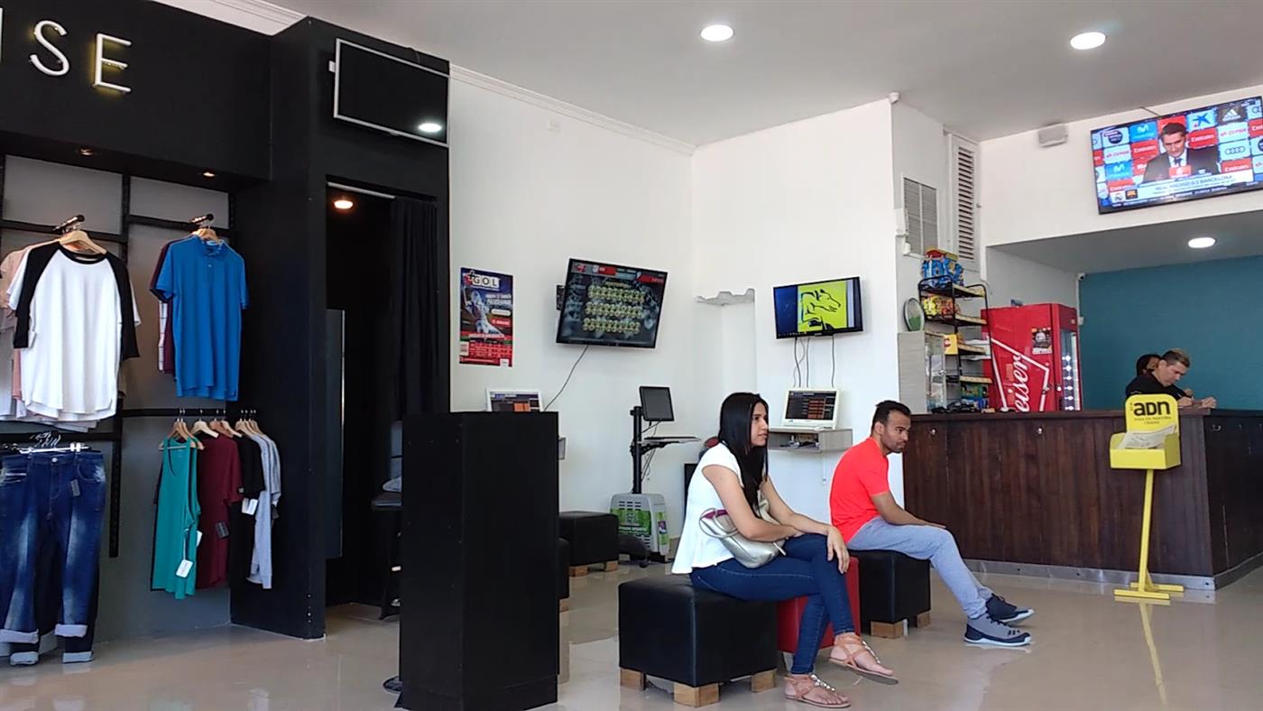 Sala de espera y recepción de Urbano con televisores y ropa en exhibición
