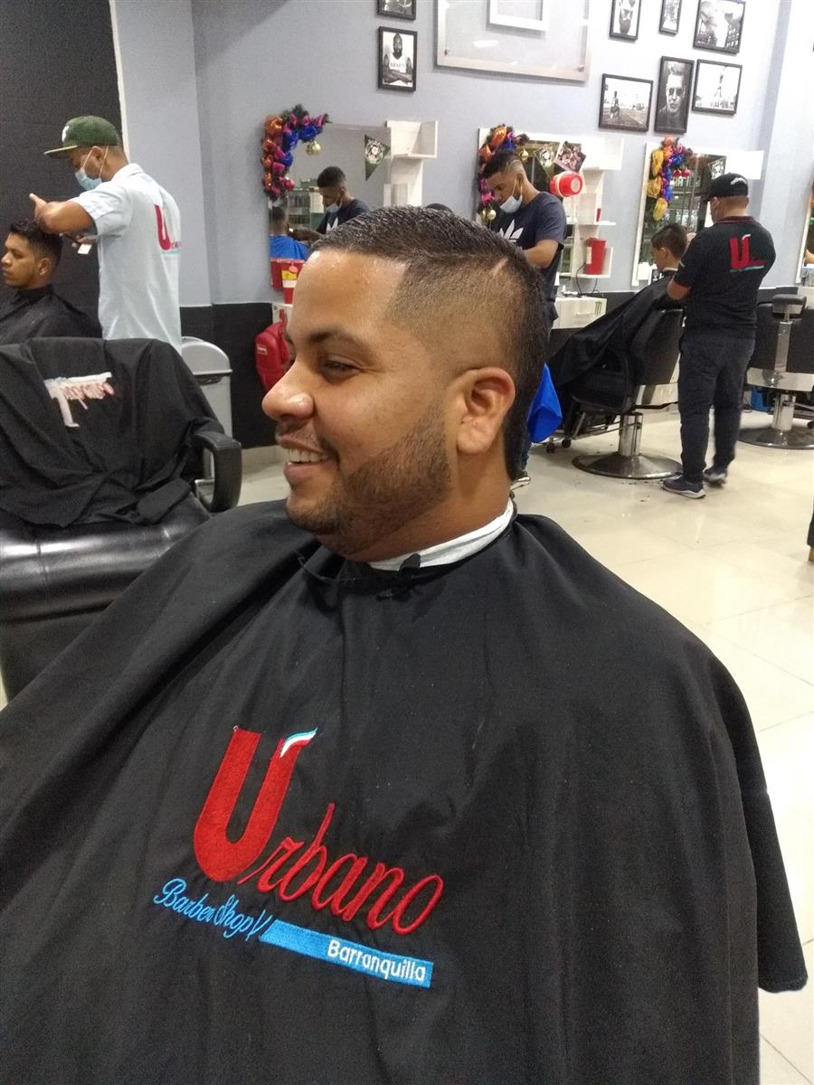 Cliente sonriente con la capa de Urbano Barber Shop