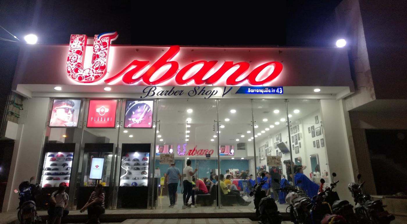 Fachada de Urbano Barber Shop de noche con su letrero rojo de neón