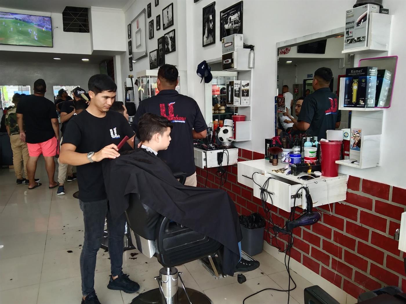 Barbero de Urbano cortando el cabello junto al muro de ladrillo rojo